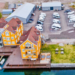 Flyfoto av bobilparkeringen og de gule husene ved kaia på Danholmen